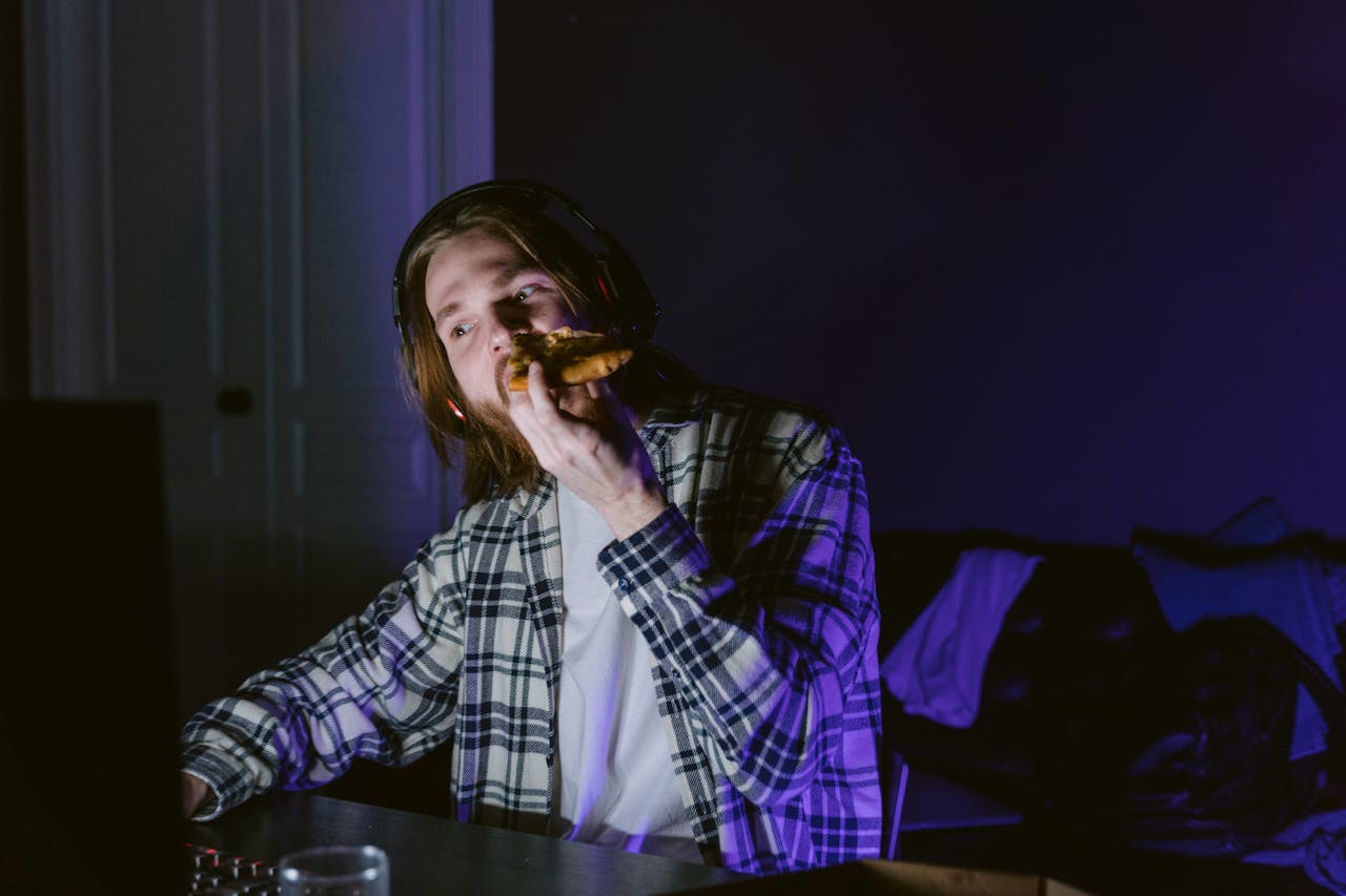 The Art of Drawing Readers In: Your attractive post title goes here A young man enjoys gaming with headphones while eating pizza in a dimly lit room.