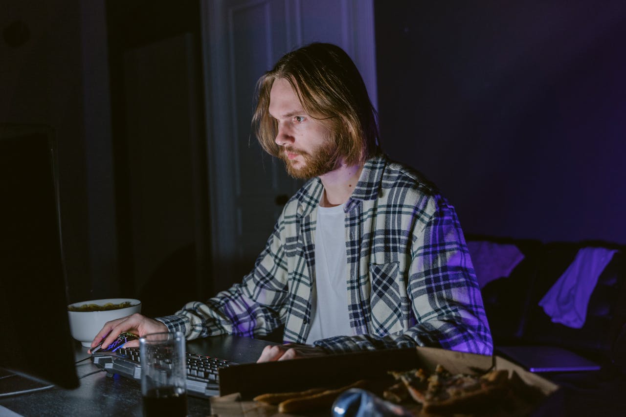 Mastering the First Impression: Your intriguing post title goes here Young man intensely gaming on a computer in a dimly lit room at night.
