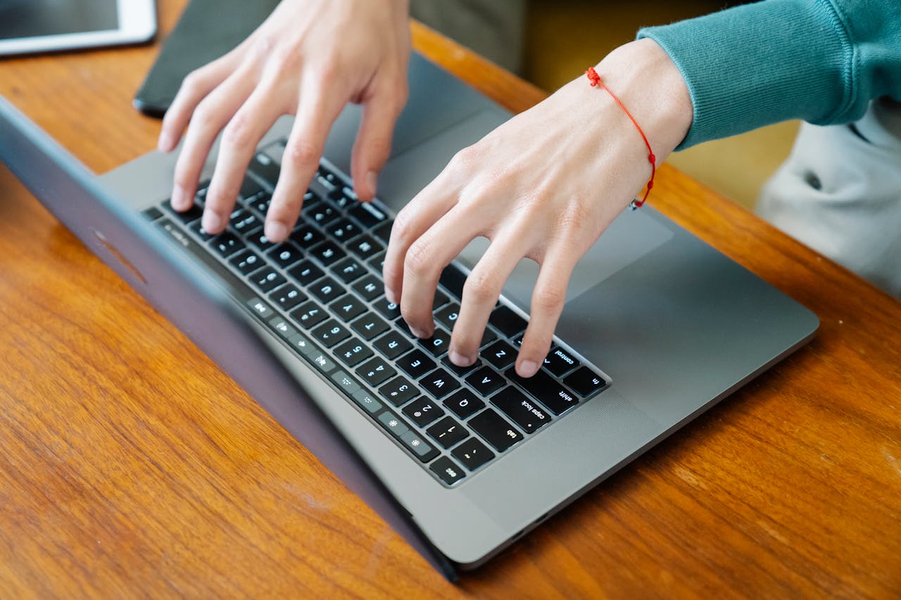 The Art of Drawing Readers In: Your attractive post title goes here Close-up of hands typing on a laptop keyboard at a wooden table, perfect for remote work concepts.