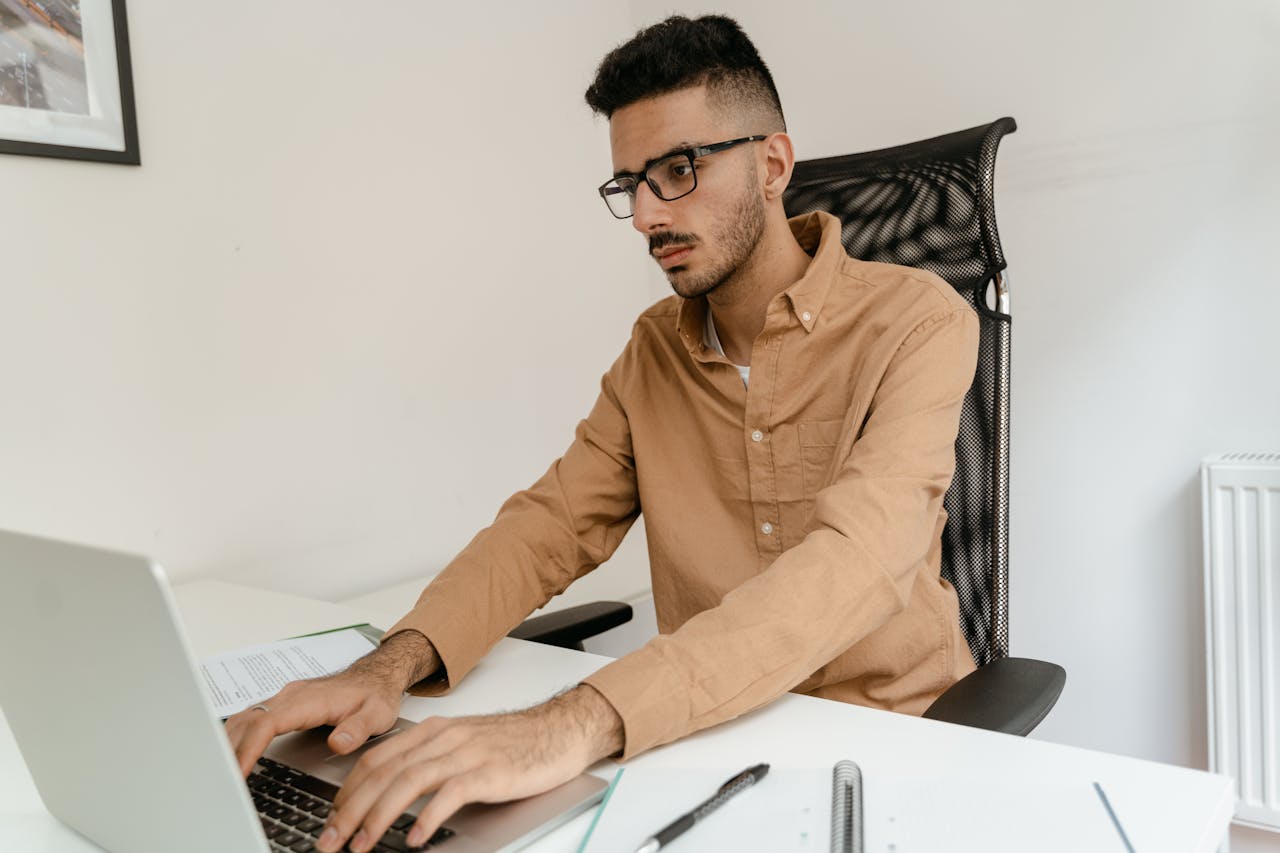 The Art of Drawing Readers In: Your attractive post title goes here Man in brown shirt working on laptop, focused and indoors.